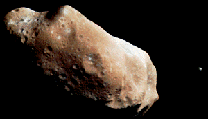 An asteroid, with a mottled brown surface showing many small depressions and a lumpy overall shape rather like a potato.