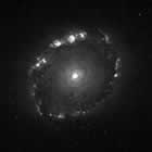 Black and white spiral galaxy image at yellow   wavelengths, showing the outskirts of spiral arms and a bright central nucleus.