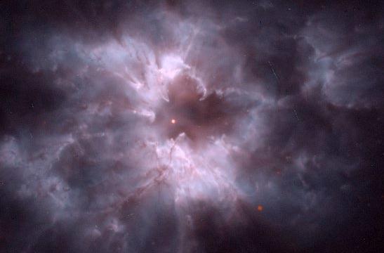 Planetary nebula NGC 2440: The central white dwarf is a small reddish-white dot in the center of the image, surrounded by large purple and white disordered shells of gas with evident substructure.