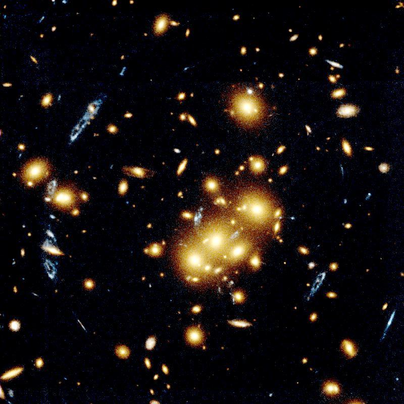 Hubble Space Telescope image of the galaxy cluster CL0024+1654. In the foreground we find a large collection of large, golden galaxies which form the cluster population. The multiple blue extended circles and arcs are all images of a single distant ring-shaped galaxy located far beyond the cluster. The blue arcs are distributed about the center of the galaxy cluster, and have a variety of sizes and aspect ratios determined by the complex mass distribution of the foreground galaxies.