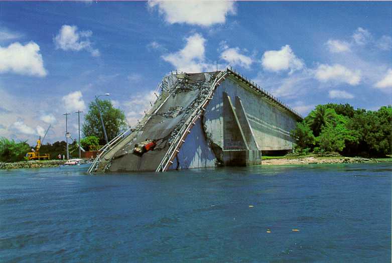 Palau bridge after collapse, showing close-up of collapsed concrete segment covered with debris.