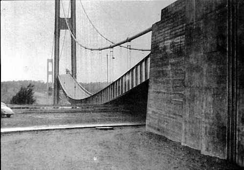 The bridge after having been torn from its vertical posts, sagging down into the water below.