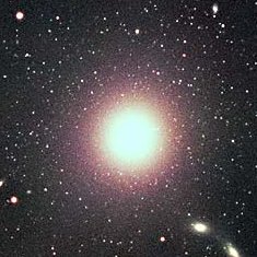 Telescope image of elliptical galaxy NGC 4486, a bright yellow sphere of stars.