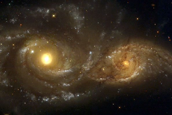 Telescope image of two interacting spiral galaxies. The smaller one shows more distortion in structure, and will eventuially be subsumed into the larger.